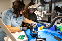 Jabil’s solder training specialist, Elizabeth Campagna, demonstrates a technique for Mariah O'Neal, who earned her soldering certification at St. Petersburg College and now works as a solderer at Jabil.