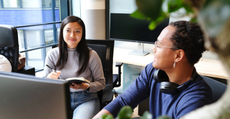 Two people talking at their desks